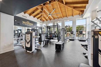 a spacious fitness center with cardio equipment and large windows